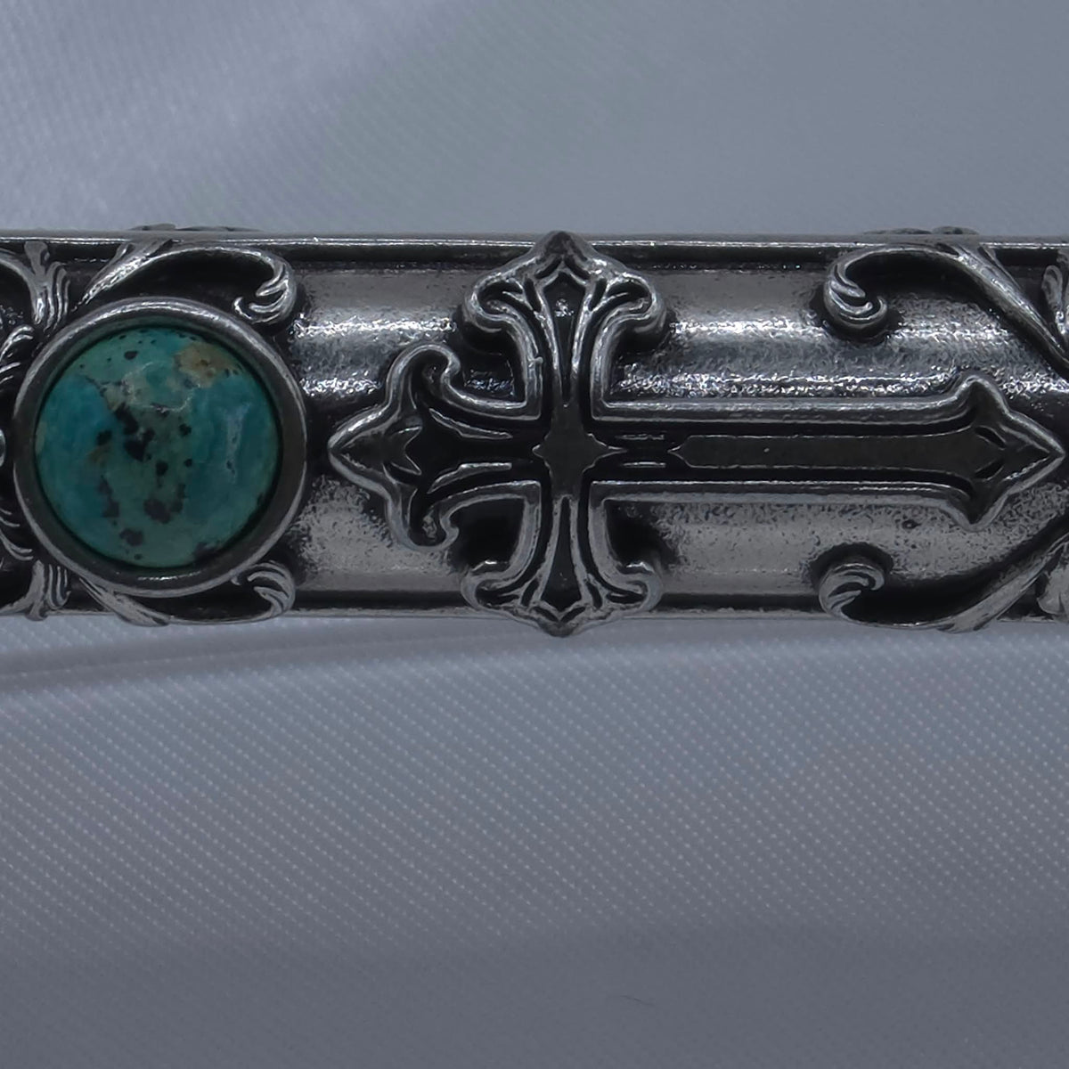 Macro detail of the lower shaft of the Moriah Cross Works Bible Reading Pointer in antiqued silver, showing the raised cross motif and King Solomon Stone cabochon with deep shadow contrast from the antiquing treatment