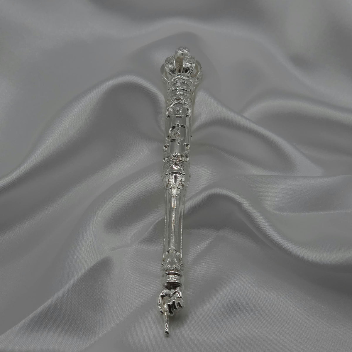 The Moriah Cross Works BR-BRSP-001 Bible Reading Pointer back view in bright mirror-polished silver, full length view showing the ornate crown, filigree shaft, and pointing hand, resting on grey silk