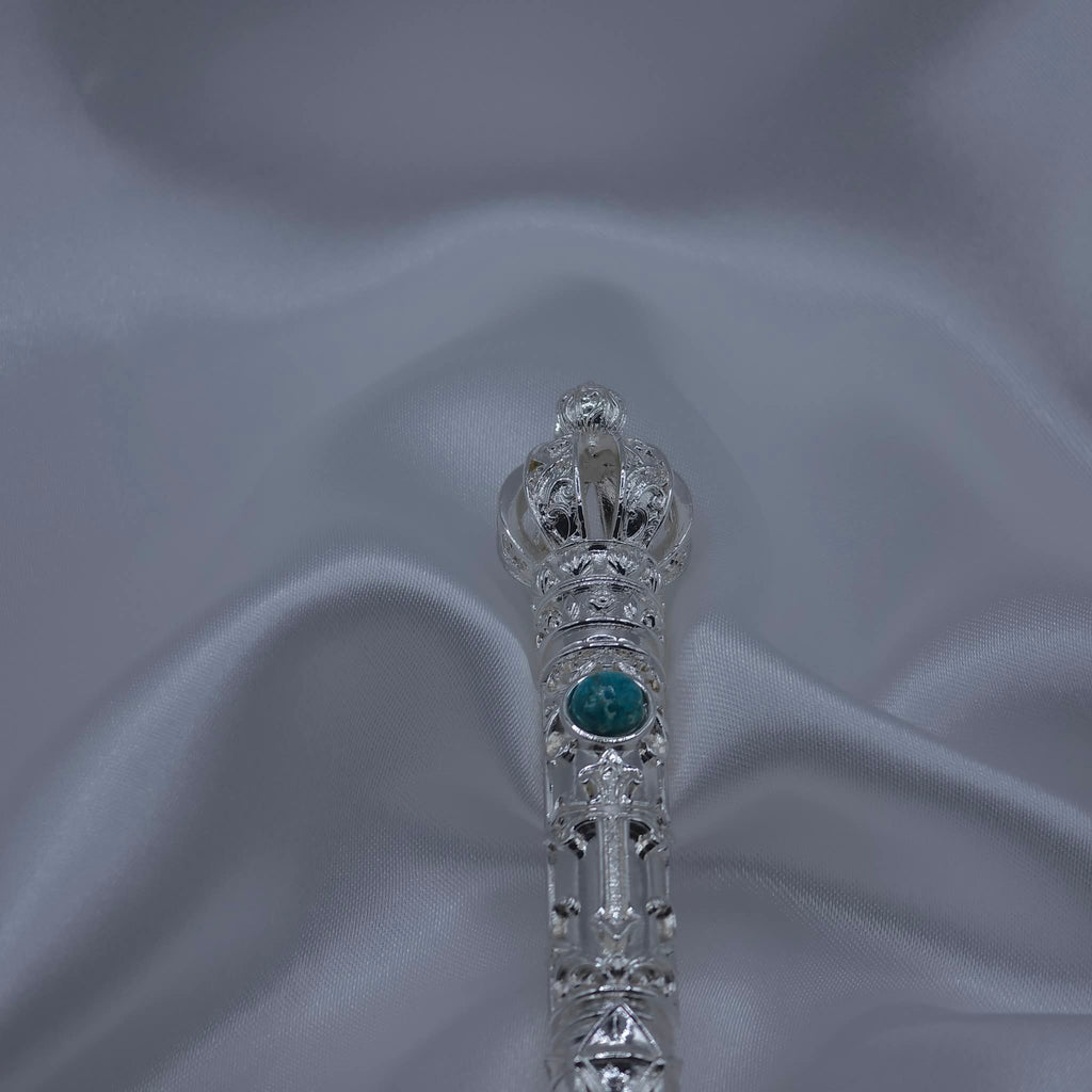 Close-up detail of the crown and upper shaft of the Moriah Cross Works Bible Reading Pointer in bright silver, showing the ornate filigree cage crown and King Solomon Stone cabochon set into the shaft