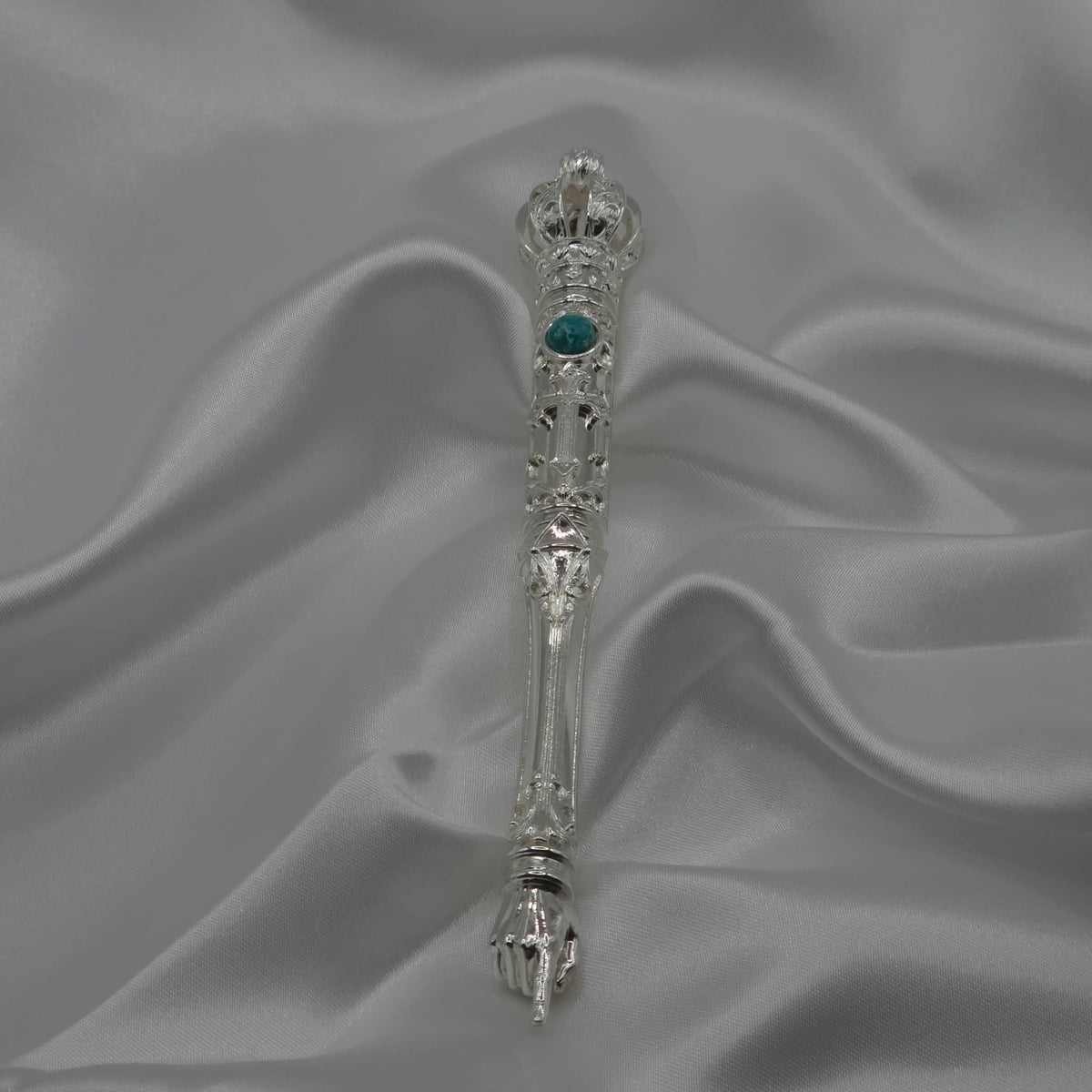 The Moriah Cross Works BR-BRSP-001 Bible Reading Pointer in bright mirror-polished silver, full length view showing the ornate crown, filigree shaft, and pointing hand, resting on white satin