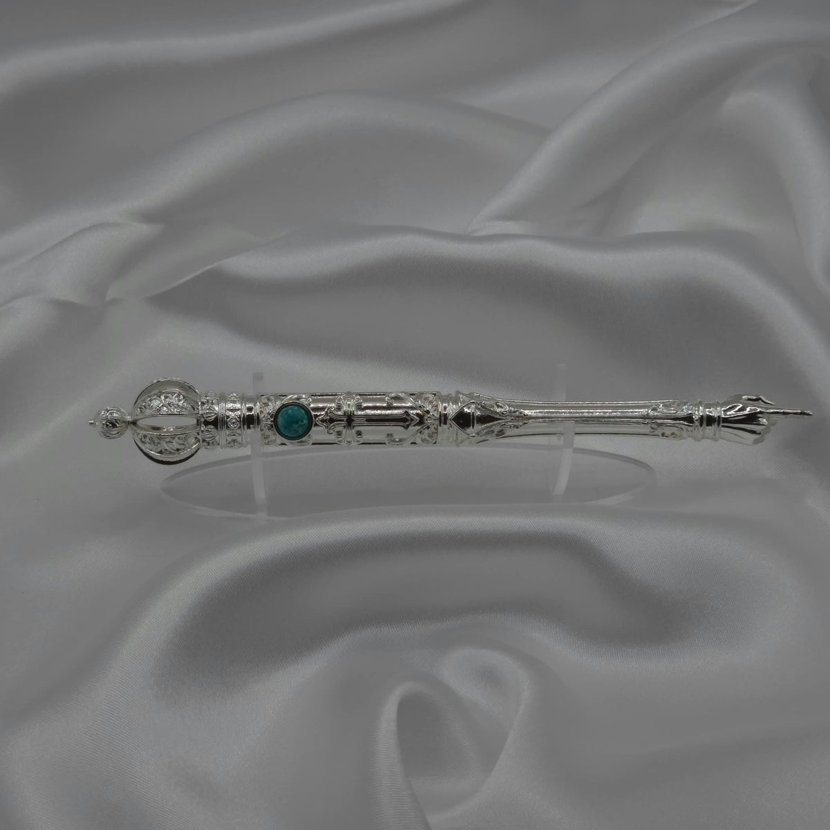 The Moriah Cross Works BR-BRSP-001 Bible Reading Pointer in bright silver displayed horizontally on grey silk, showing the full length of the piece with the King Solomon Stone cabochon and ornate pointing hand visible