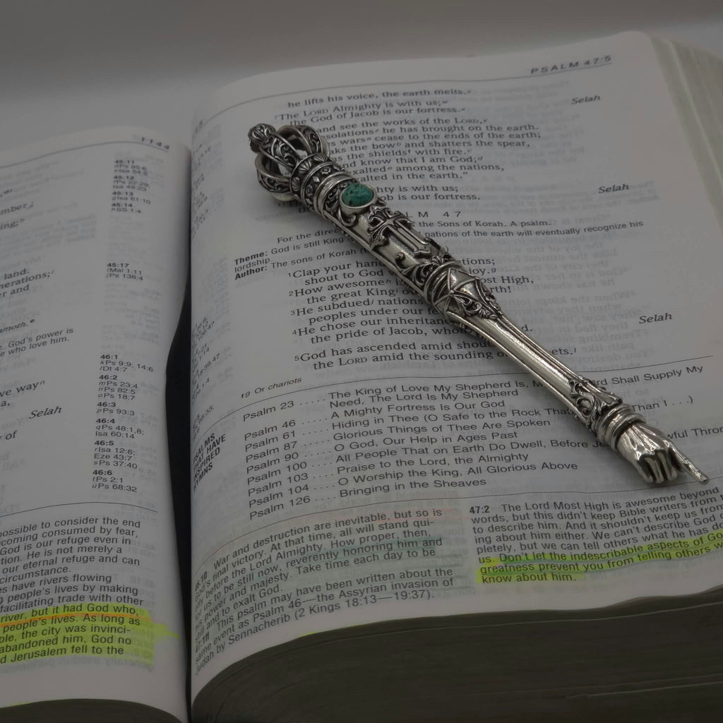 The Moriah Cross Works BR-BRSP-001 Bible Reading Pointer sample in antiqued silver, resting open on a Bible open to the Psalms, with the King Solomon Stone cabochon visible on the shaft and the ornate pointing hand resting on the scripture text