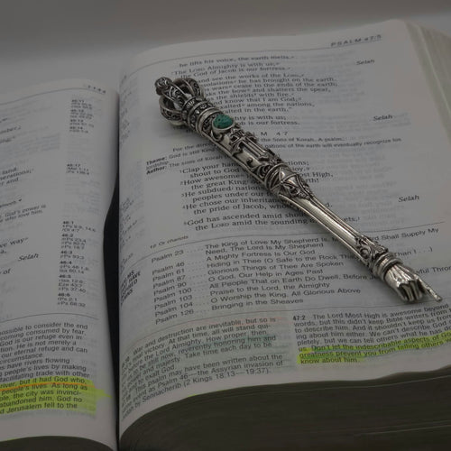 The Moriah Cross Works BR-BRSP-001 Bible Reading Pointer sample in antiqued silver, resting open on a Bible open to the Psalms, with the King Solomon Stone cabochon visible on the shaft and the ornate pointing hand resting on the scripture text