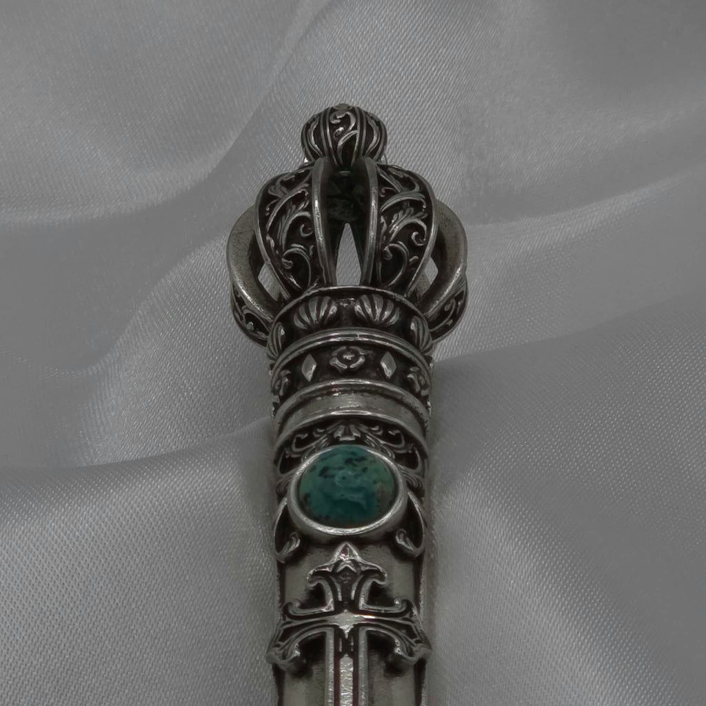 Close-up vertical detail of the filigree crown and upper shaft of the Moriah Cross Works Bible Reading Pointer in antiqued silver, showing deep shadow contrast between the raised ornaments and recessed background, with King Solomon Stone set below the crown