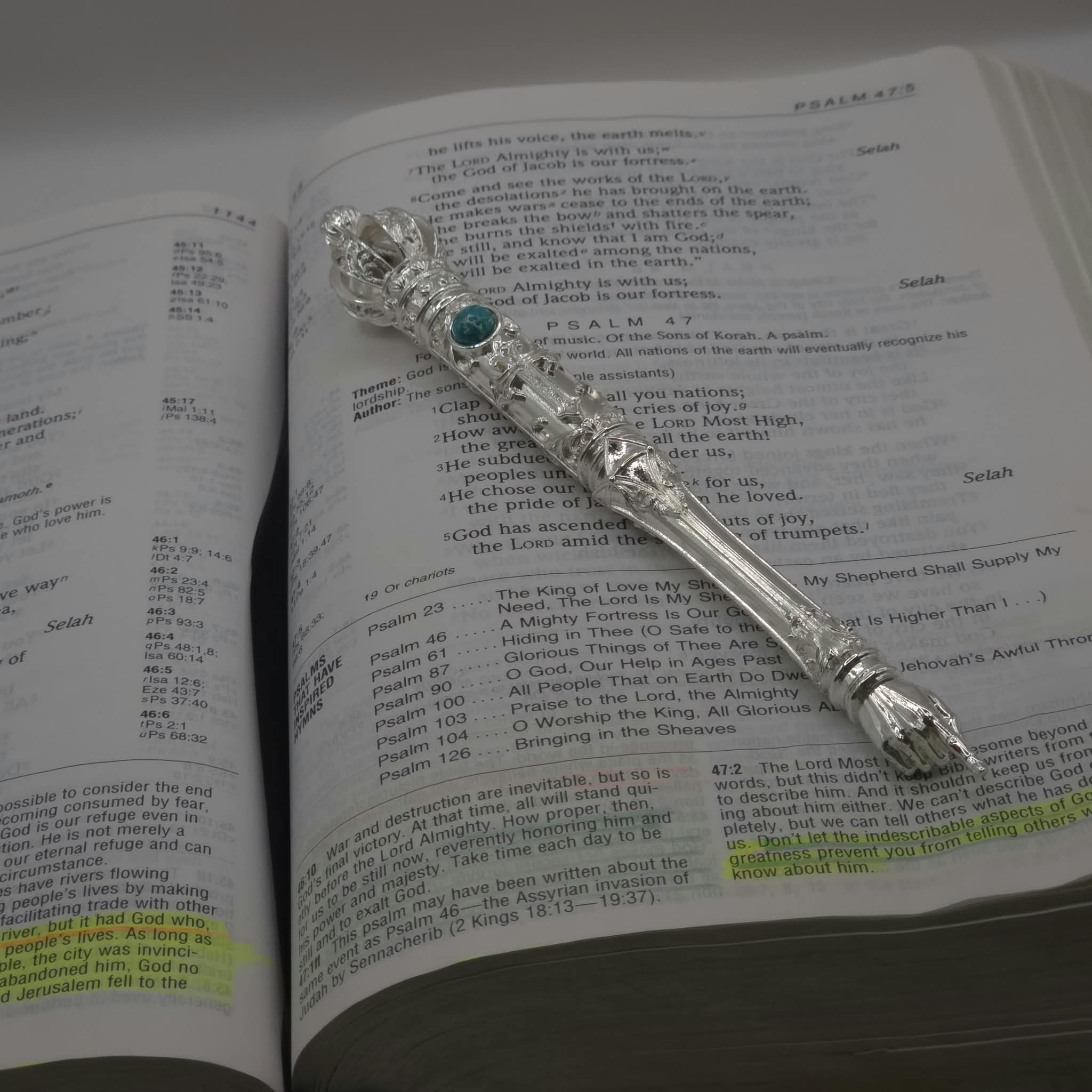 The Moriah Cross Works BR-BRSP-001 Bible Reading silver Pointer sample, resting open on a Bible open to the Psalms, with the King Solomon Stone cabochon visible on the shaft and the ornate pointing hand resting on the scripture text