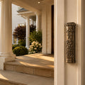 Silver Christian doorpost scripture holder mounted beside a front door, engraved "Bless this Home," on a sunlit porch entrance lifestyle image